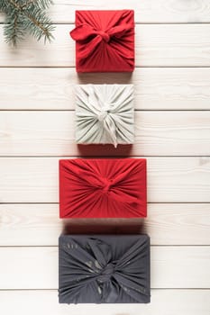 Group of christmas presents in furoshiki package, top view. Spruce branch and gift boxes on white planking. Objects layout in ascending size. Christmas or New Year holiday, eco decor, zero waste.
