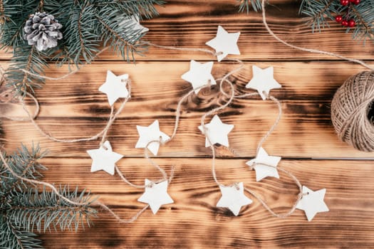 Christmas stars homemade cold porcelain garland with spruce branches on background of burnt wood. Top view