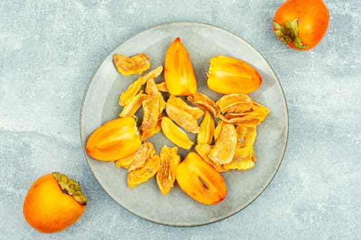 Sweet dried persimmon on the plate. Healthy vegan snacks. Copy space