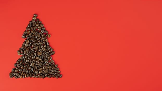 Brown coffee beans laid out in shape of Christmas tree on red background. Banner. Flat lay. Copy space