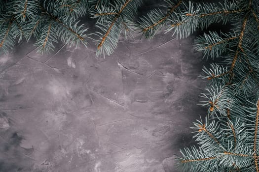 Background image of gray uneven concrete surface with Christmas tree branches. Top view, copy space