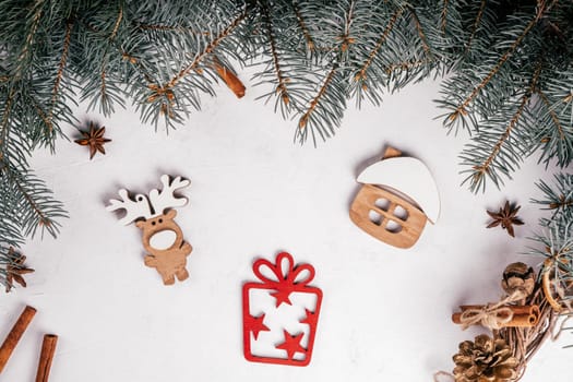 White uneven concrete surface with Christmas tree branches, cinnamon, anise and wooden decorations House, Elk, Gift. Top view.