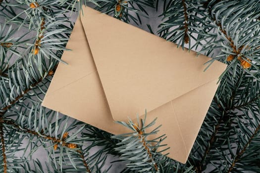 Background creative image with close up texture of fir branches with beige kraft paper envelope. Merry christmas and happy new year. Top view. Copy space
