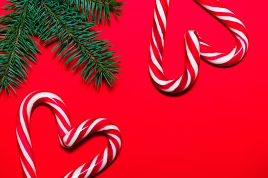 Lollipop hearts on red surface with Christmas tree branches. Christmas and New Year greeting card