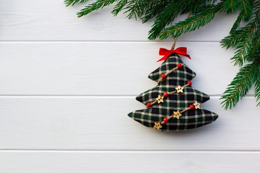 Green branches of a Christmas tree with DIY soft decoration on a background of white boards. Flat lay, copy space.