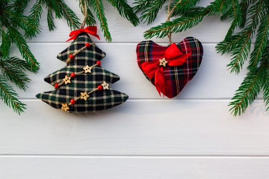 Green branches of a Christmas tree with DIY soft decoration on a background of white boards. Flat lay, copy space.