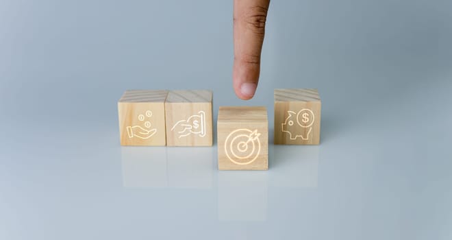 Hand pointing at one wood cube block with target icon . Concept of business strategy and goal action plan.