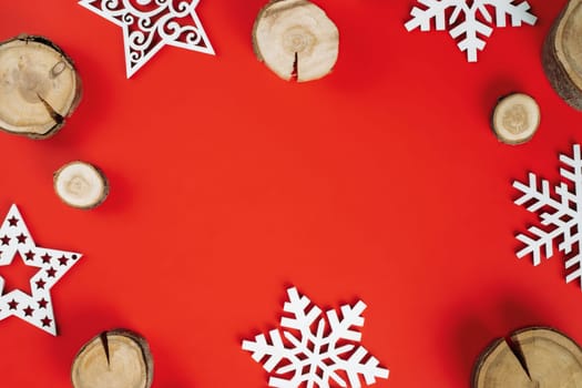 Wood cuts or branch slabs and wooden snowflakes on red background. Christmas or New Year concept. Flat lay. Copy space
