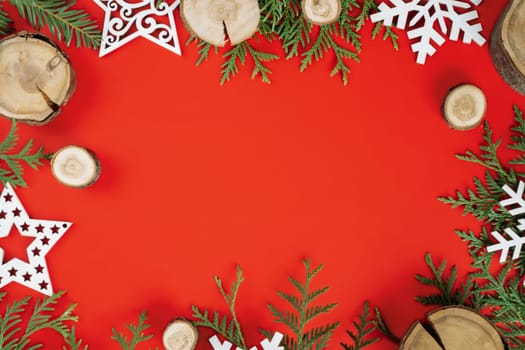 Wood cuts or branch slabs and wooden snowflakes with Christmas tree branches on red background. Christmas or New Year concept. Flat lay. Copy space