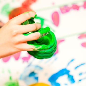 Child holding finger paint brush close-up