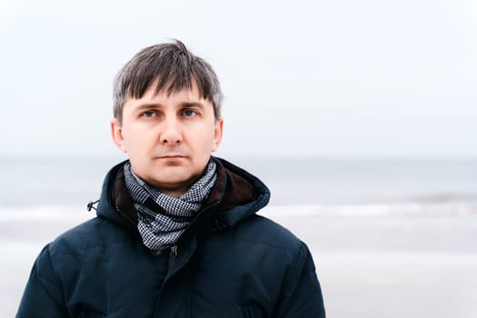 Portrait of a serious relaxed middle-aged man near the winter sea.