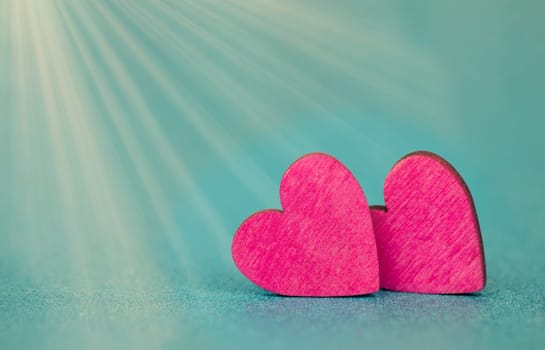 Pink hearts on a turqouise background with sunbeams, valentine greeting card, mothers day and birthday wishes, love symbol