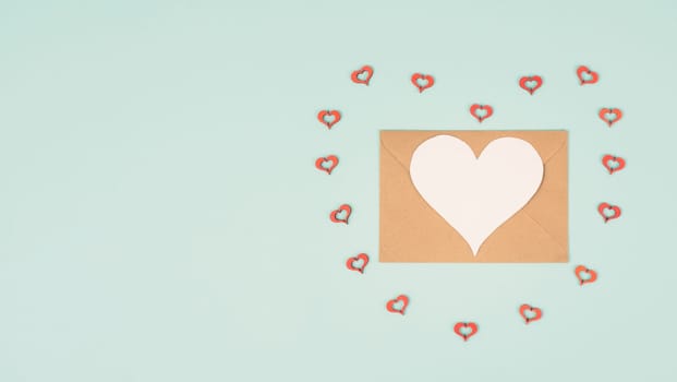 Valentine day greeting card, envelope with hearts on pastel background, love symbol, flat lay