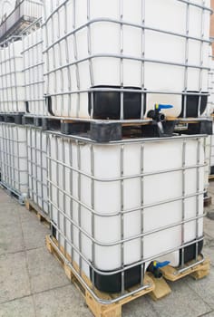 Lots of cube water tanks. 1000 litres containers piled outdoors