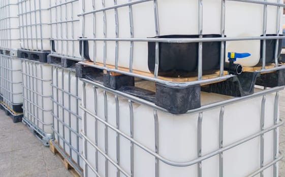 Lots of cube water tanks. 1000 litres containers piled outdoors