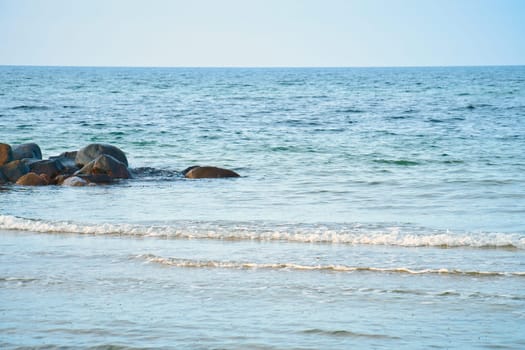 Stone groynes, breakwaters in the water off the coast in Denmark. Sunny day while hiking. Landscape photo by the sea