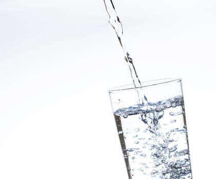 The image of pouring drinking water, into a glass, that makes one feel refreshed on blurred white background, Splashing water, Sparkling water