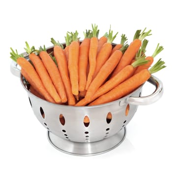 Baby carrots with stalks in a brushed stainless steel colander, isolated over white background.