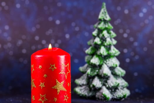 burning candle with snowy fir tree in the background