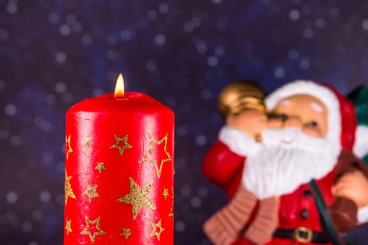burning candle with Santa Claus in the background