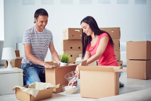 Young couple unpacking boxes after removing to new house