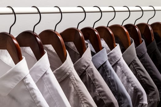 Several shirts on a hanger. from white to black color range.