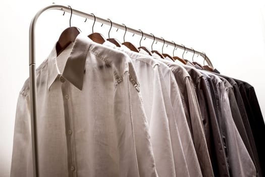 Several shirts on a hanger. from white to black color range.