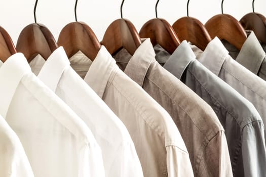 Several shirts on a hanger. from white to black color range.