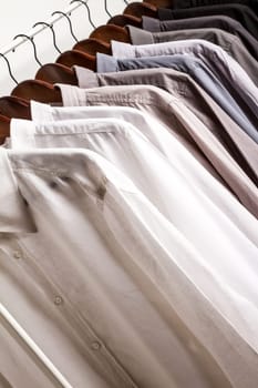 Several shirts on a hanger. from white to black color range.
