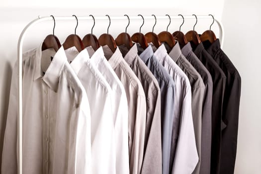 Several shirts on a hanger. from white to black color range.