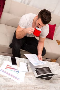 Businessman working at home in the laptop and drinking coffee.
