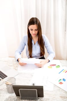 Businesswoman working at the office with the laptop and some documents.