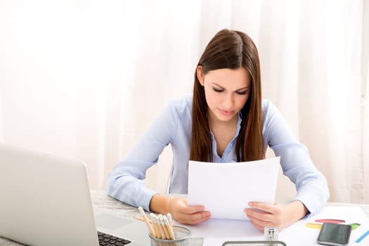 Businesswoman working at the office with the laptop and some documents.