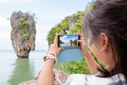 Women tourist he is shooting a beautiful scenic view by mobile phone at Khao Tapu or James Bond Island in Ao Phang Nga Bay National Park, Thailand
