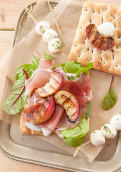 Sandwich with raw ham,grilled peaches and mozzarella