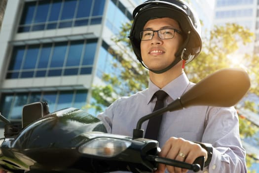 Young asian businessman commuting to job in the morning. The man rides a motorcycle scooter with white helmet and looks away