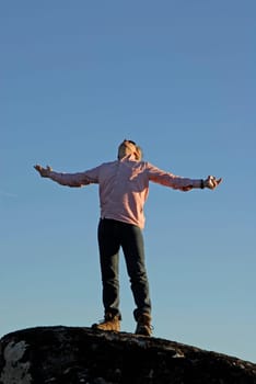 young man with arms wide open and the sky as background