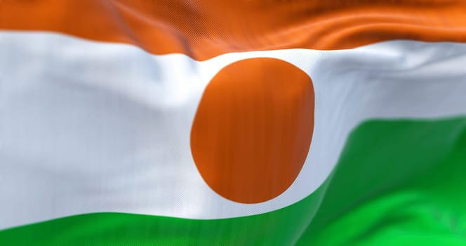 Close-up view of the Niger national flag waving. Republic of the Niger is a landlocked country in West Africa. Fabric textured background. Selective focus. 3D illustration