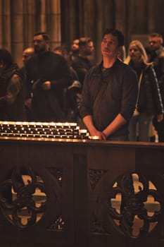 Vertical shot of people holding devotions in front of a sea of candles at Cologne Cathedral, Germany