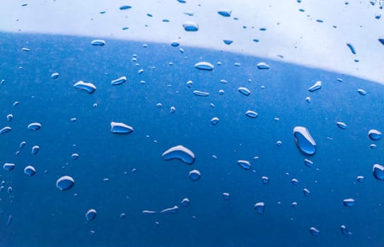 Landscape of drops on the car body after washing it with a pressure gun. Light blue
