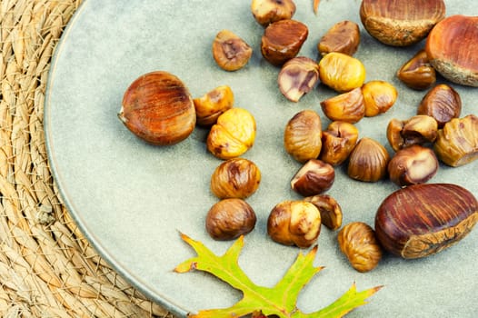 Fried peeled chestnuts on the plate. Delicious treat: roasted chestnuts.