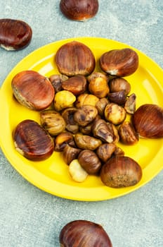 Fried peeled chestnuts on the plate. Delicious treat: roasted chestnuts.