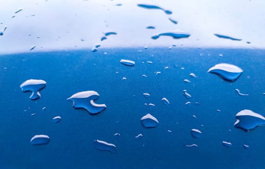 Landscape of drops on the car body after washing it with a pressure gun. Light blue