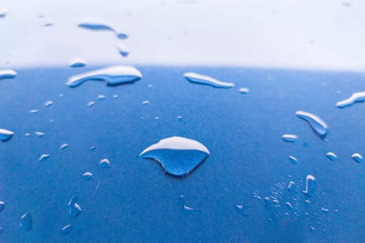 Landscape of drops on the car body after washing it with a pressure gun. Light blue