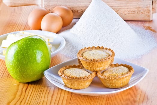 Freshly made apple pies on the table with flour eggs apple and  butter