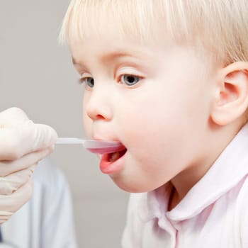 Doctor giving a spoon of syrup to cute little girl