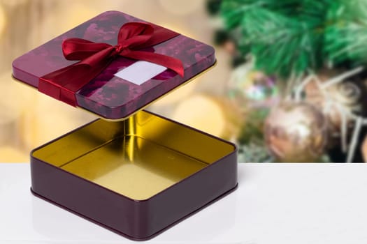 Empty opened decorative red pink gift or gift box with bow on a table over an abstract blurred Christmas background. Copy space.