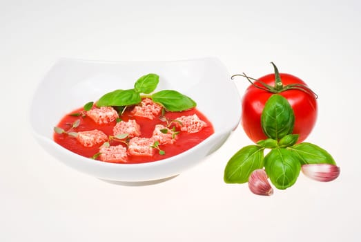 Bowl of tomato soup with tomato, basil and garlic over  white background