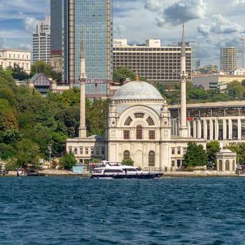 Istanbul, Turkey - August 29, 2022: View from Bosphorus Strait overlooking baroque waterside Dolmabahce Mosque, suited at the waterside of Kabatas, in Beyoglu district