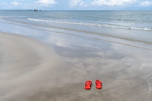 Red shoes on  sand beach with sea background